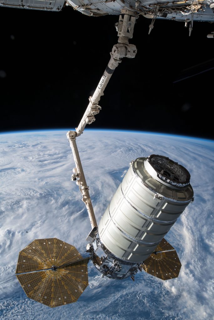 The Orbital ATK space freighter is slowly maneuvered by the Canadarm2 robotic arm